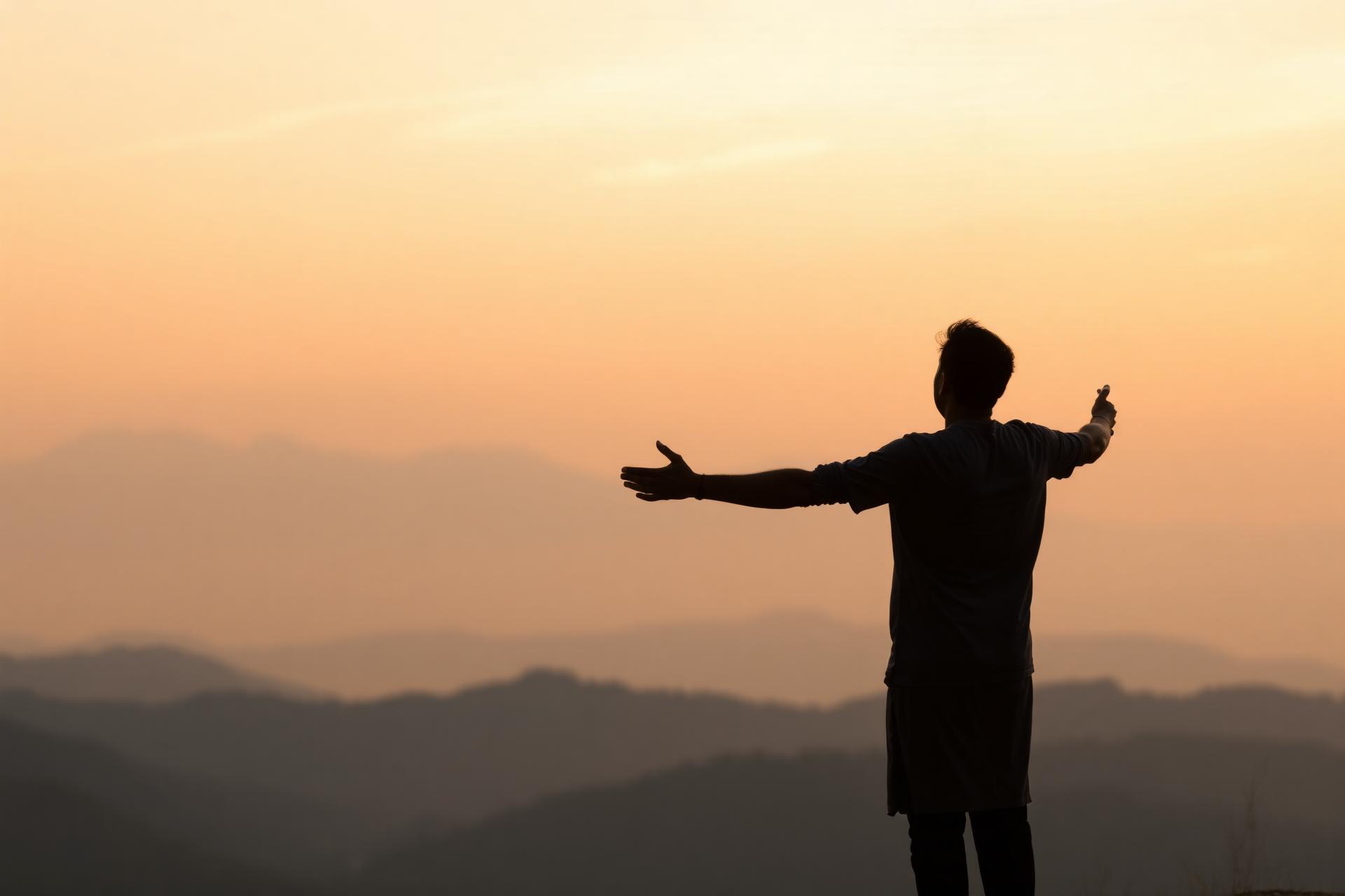 सूर्योदय की ओर देखता हुआ व्यक्ति